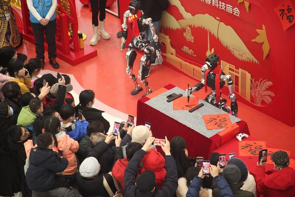  زوار يستمتعون ويلتقطون الصور لروبوتات تؤدي عرضًا في معرض للعلوم والتكنولوجيا في بكين في الصين - سبوتنيك عربي