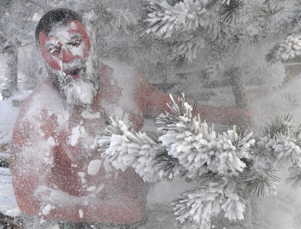 عضو في نادي "كريوفيلي" للسباحة الشتوية يرش نفسه بالثلج، بعد السباحة في نهر ينيسي في يوم بارد، في جزيرة أوتديها في كراسنويارسك، روسيا. - سبوتنيك عربي