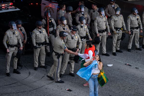 يتحدث أحد المحتجين مع ضابط شرطة بينما يسد آخرون حركة المرور على الطريق السريع خلال تجمع لدعم المهاجرين ردًا على سياسات إدارة ترامب الجديدة في 2 فبراير 2025 في لوس أنجلوس.  - سبوتنيك عربي