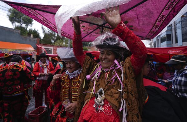 يقي الراقصون أنفسهم من المطر خلال افتتاح موسم الكرنفال في لاباز.  - سبوتنيك عربي