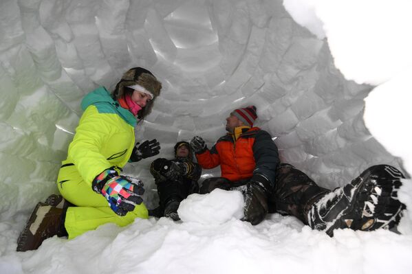 زاور مهرجان بناء الأكواخ الثلجية في نوفوسيبيرسك، يستمتعون بقضاء وقتهم داخل أحد الأكواخ الثلجية - سبوتنيك عربي