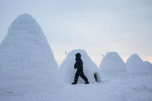 طفل يمشي بين مجموعة من الأكواخ الثلجية خلال فعاليات مهرجان بناء الأكواخ الثلجية في نوفوسيبيرسك - سبوتنيك عربي