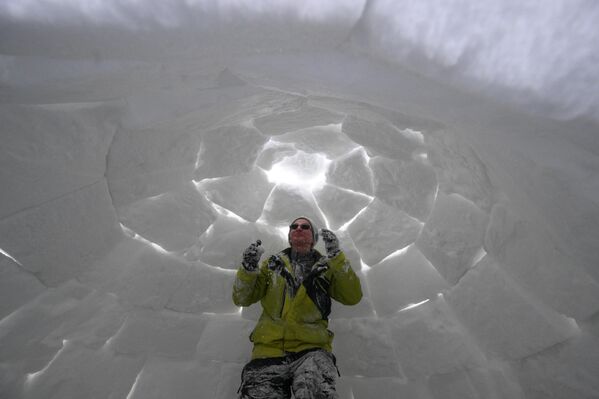 أحد زوار مهرجان بناء الأكواخ الثلجية في نوفوسيبيرسك، يستمتع بقضاء وقته داخل أحد الأكواخ الثلجية - سبوتنيك عربي