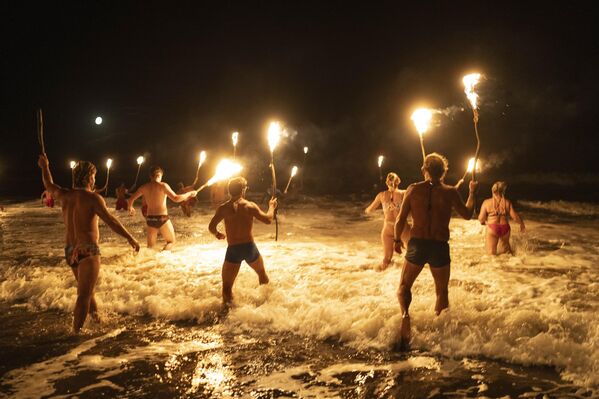 رجال الإنقاذ يحملون المشاعل في المحيط الأطلسي، في احتفال لإحياء ذكرى يوم رجال الإنقاذ، لتكريم التزامهم بالسلامة والإنقاذ المائي، في مار أزول، الأرجنتين. - سبوتنيك عربي