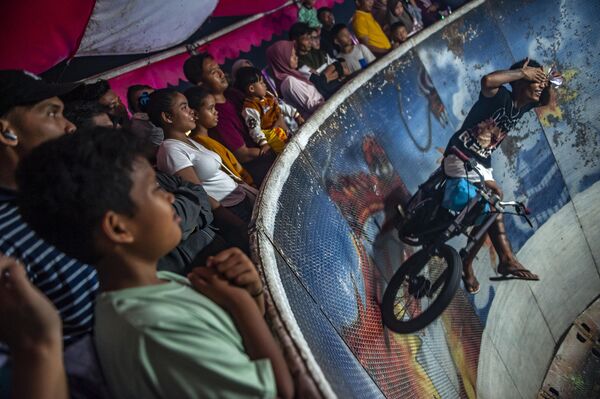 رياضيون يستعرضون مهاراتهم في عرض ترفيهي خلال مهرجان "رودا جيلا" في سوق ليلي تقليدي في ديلي سيردانغ، أندونيسيا. - سبوتنيك عربي