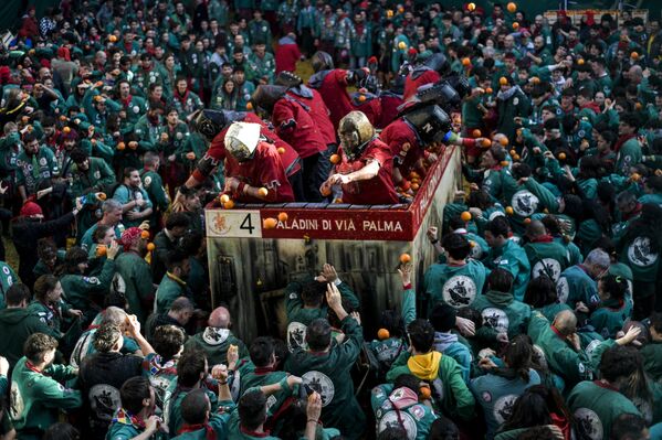 المشاركون يرمون البرتقال على فريق معركة البرتقال "I Tuchini del Borghetto Aranceri" الذي شارك في "معركة البرتقال" التقليدية في 4 مارس 2025 في إيفريا، إيطاليا. - سبوتنيك عربي