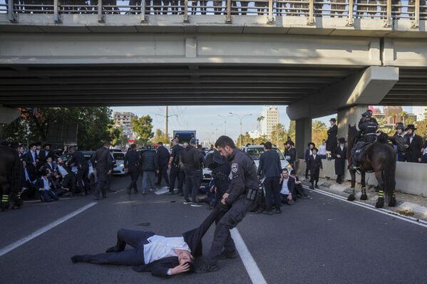 ضباط الشرطة الإسرائيلية يفرقون رجالاً يهودًا متشددين يغلقون طريقًا سريعًا أثناء احتجاج على التجنيد في الجيش في بني براك، إسرائيل، الأحد 2 مارس 2025. - سبوتنيك عربي