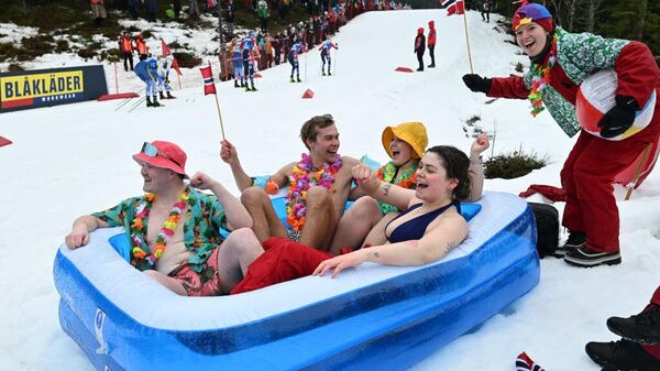 طلاب نرويجيون يرتدون ملابس السباحة، يشاهدون سباق التزلج أثناء الجلوس في حمام سباحة قابل للنفخ في النرويج - سبوتنيك عربي