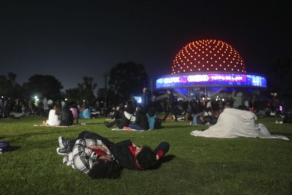 يستلقي الناس على العشب خارج القبة السماوية أثناء مشاهدتهم خسوف القمر الكلي في بوينس آيرس، الأرجنتين، الجمعة 14 مارس 2025. - سبوتنيك عربي