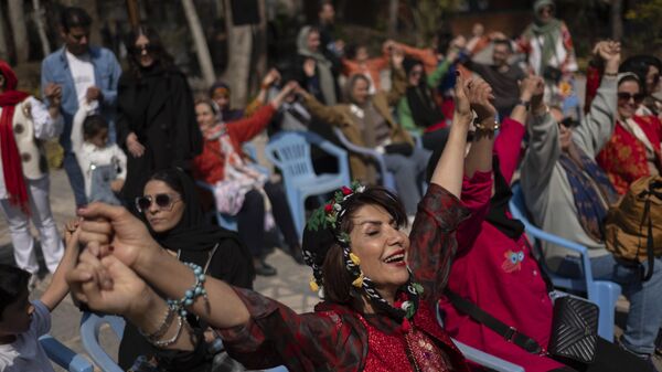 نساء إيرانيات يتشابكن في إشارة إلى الوحدة، يشاركن في احتفال استقبال عيد النوروزأمام متحف السينما شمالي طهران - سبوتنيك عربي