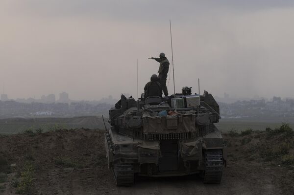 جنود إسرائيليون على متن دبابة أثناء تمركزها أمام شمال قطاع غزة - سبوتنيك عربي