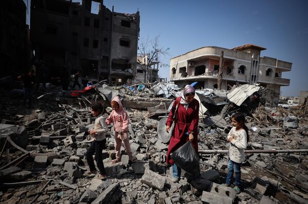 سيدة وأطفالها بين أنقاض منزل بعد تدميره من قبل غارة إسرائيلية على مدينة غزة - سبوتنيك عربي