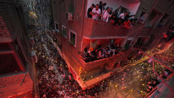 سكان عزبة حمادة في حي المطرية بالقاهرة يطلون من شرفاتهم للاحتفال بإفطار جماعي، وهو الوجبة التي يختتمون بها صيامهم عند غروب الشمس، خلال شهر رمضان المبارك في القاهرة، مصر، السبت 15 مارس/آذار 2025. - سبوتنيك عربي