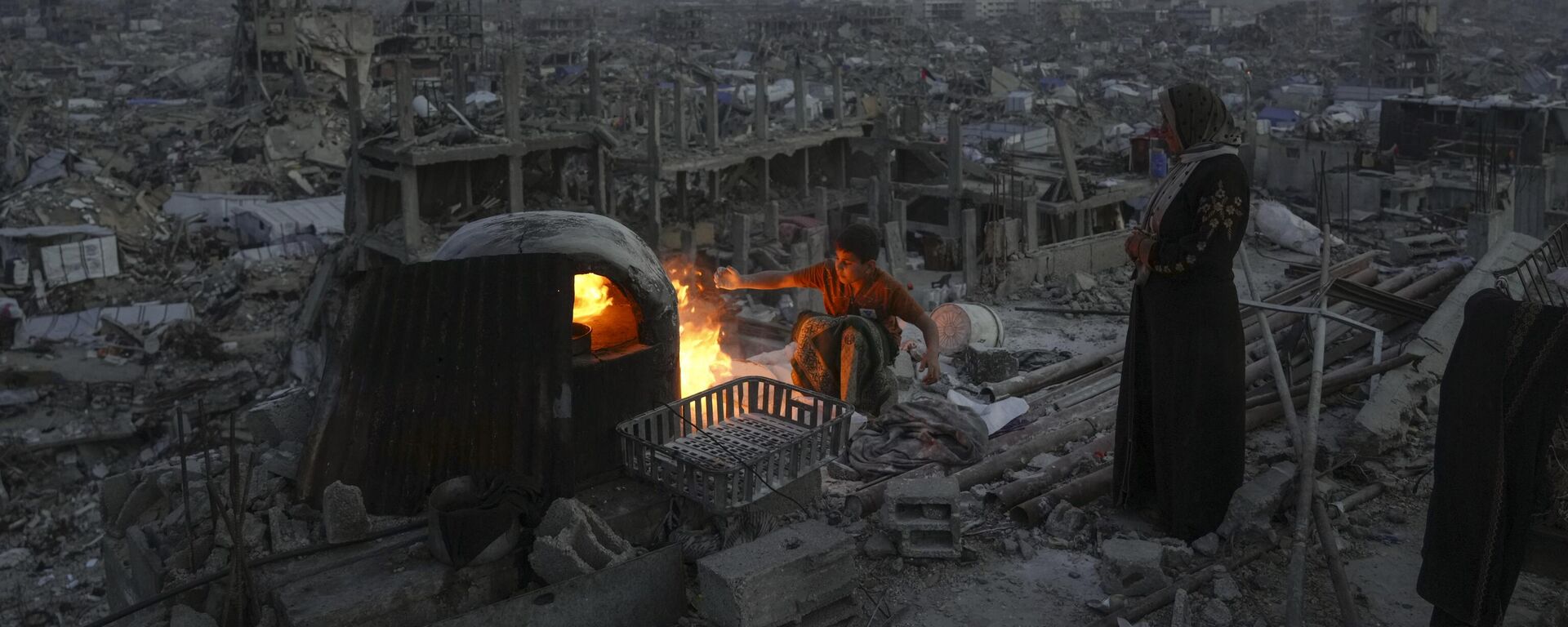 الفلسطيني علي معروف ووالدته عائشة يطبخان على النار على سطح منزلهما المدمر جراء الهجوم الجوي والبري الذي شنه جيش الاحتلال الإسرائيلي على جباليا، قطاع غزة، يوم الاثنين 17 مارس/آذار 2025. - سبوتنيك عربي, 1920, 23.03.2025