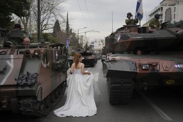 امرأة ترتدي زي عروس وتسير بين الدبابات خلال جلسة تصوير قبل عرض عسكري لإحياء ذكرى بدء حرب الاستقلال اليونانية، عام 1821، ضد الحكم العثماني في أثينا. - سبوتنيك عربي