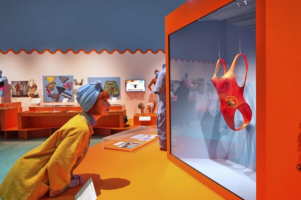 امرأة تنظر إلى ملابس السباحة التي ارتدتها باميلا أندرسون في فيلم "بايواتش"، والمعروضة في معرض "سبلاش"، في متحف التصميم بلندن، المملكة المتحدة. - سبوتنيك عربي