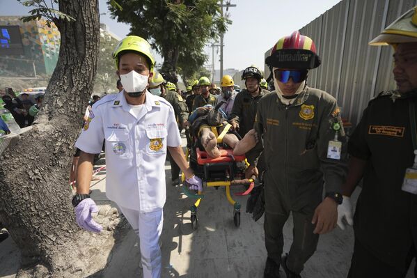 رجال الإنقاذ يحملون أحد المصابين من موقع ناطحة سحاب قيد الإنشاء انهار بعد زلزال بقوة 7.7 درجة على مقياس ريختر في بانكوك، تايلاند. - سبوتنيك عربي