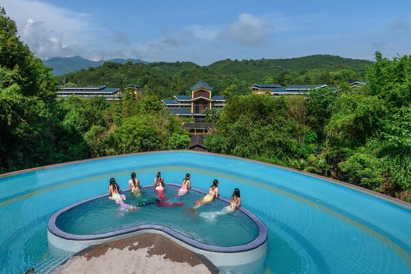سائحون يرتدون ملابس حوريات البحر يسبحون في حوض سباحة على شكل قلب في منتجع لونغمين للينابيع الساخنة في هويتشو في مقاطعة قوانغدونغ الصينية. - سبوتنيك عربي