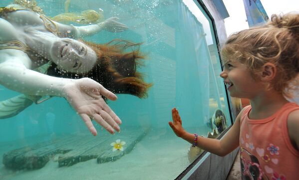 فتاة تنظر إلى "حورية بحر" تسبح خلال مهرجان السفن الشاهقة السنوي الحادي والثلاثين لمعهد المحيط. - سبوتنيك عربي