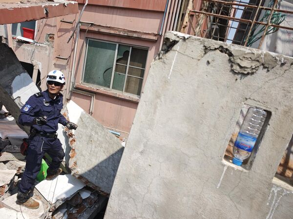 رجل إنقاذ صيني يبحث عن ناجين تحت أنقاض مبنى سكني منهار ويقلب زجاجة مياه للشرب للتحذير من هزات ارتدادية محتملة في ماندالاي، ميانمار. - سبوتنيك عربي