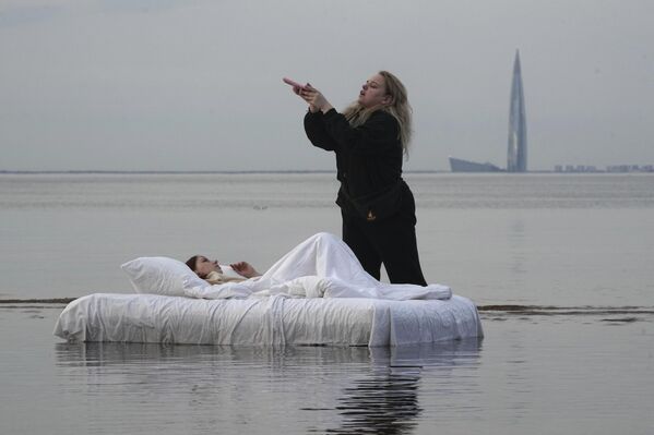 امرأة تلتقط صورة لنشرها على مواقع التواصل الاجتماعي، وهي مستلقية على فراشٍ قابل للنفخ على شكل سرير قرب ساحل خليج فنلندا في سانت بطرسبورغ، روسيا. - سبوتنيك عربي