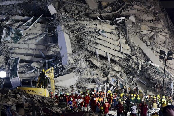 أحد الأبنية المهدّمة التي انهارت جراء الزلزال الذي ضرب في تايلاند، بقوة 7.7، ويظهر في الصورة عمال الإنقاذ مجتمعين أمام المبنى. - سبوتنيك عربي