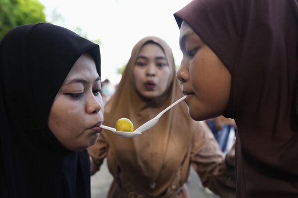 سيدات ينقلن الليمون الفلبيني باستخدام ملاعق بلاستيكية أثناء مباراة احتفالاً بعيد الفطر في حديقة في مدينة كيزون، الفلبين. - سبوتنيك عربي