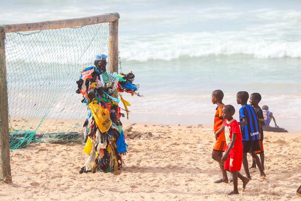 الناشط البيئي السنغالي مودو فال، المعروف أيضًا باسم "الرجل البلاستيكي"، يحمل لافتة على صدره كتب عليها "أفريقيا ليست سلة مهملات"، ويرتدي زيّ مصنوع من مئات الأكياس البلاستيكية، أثناء تنظيمه لفعالية  لتثقيف الجمهور بشأن التلوث البيئي وتغير المناخ، في داكار، السنغال. - سبوتنيك عربي