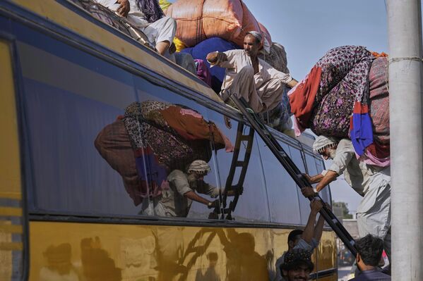 عامل يحمل أمتعة اللاجئين الأفغان على سطح حافلة في كراتشي، باكستان. - سبوتنيك عربي