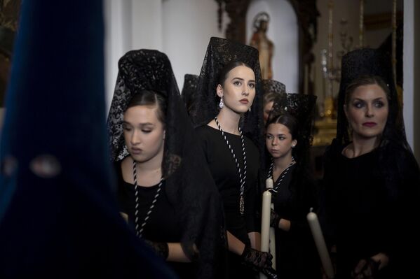 نساء يرتدين المانتيلات التقليدية ينتظرن المشاركة في موكب جماعة "إستريلا"  في مالقة، إسبانيا. يصادف أسبوع الآلام، المعروف محليًا باسم "أسبوع الآلام" - سبوتنيك عربي