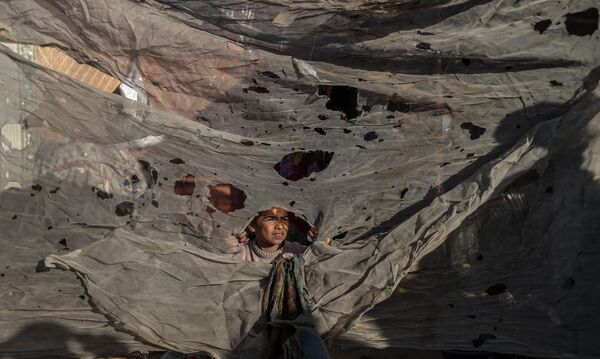 فلسطينيون يتفقدون المنطقة المتضررة بعد أن أصابت غارة جوية إسرائيلية خيامًا تؤوي المدنيين النازحين في خان يونس، غزة - سبوتنيك عربي