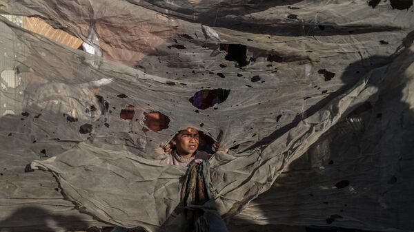 فلسطينيون يتفقدون المنطقة المتضررة بعد أن أصابت غارة جوية إسرائيلية خيامًا تؤوي المدنيين النازحين في خان يونس، غزة - سبوتنيك عربي