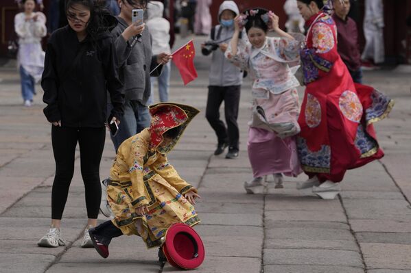 طفل يرتدي زي الإمبراطور يركض بعد أن أطاحت الرياح القوية بتاجه في بكين، الصين - سبوتنيك عربي