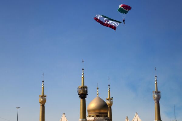  قفز مظلي لأحد عناصر الجيش وهو يحمل العلم الإيراني خلال العرض العسكري. - سبوتنيك عربي