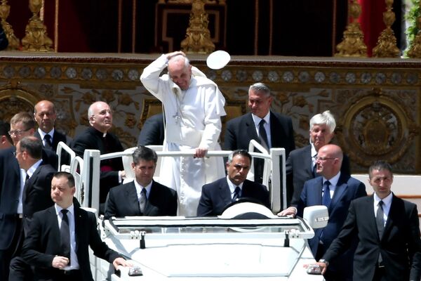 البابا فرنسيس يخلع قبعته وهو يغادر ساحة القديس بطرس على متن سيارة الباباوية بعد قداس عيد العنصرة، في مدينة الفاتيكان. - سبوتنيك عربي