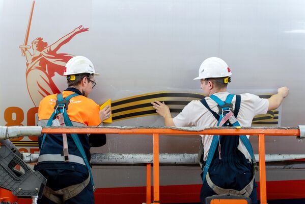 عمال يقومون بإلصاق شعار الذكرى الثمانين للنصر على طائرة &quot;إيرباص&quot; في مجمع &quot;إيروفلوت تكنيكس&quot; للطائرات. - سبوتنيك عربي