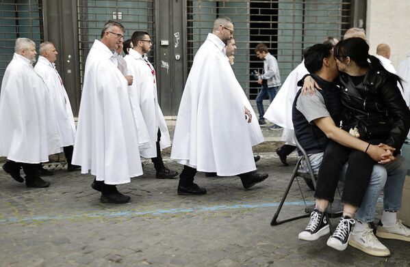 زوجان يتعانقان بينما يسير أعضاء من فرسان الهيكل الكاثوليك في موكب صامت في طريقهم للصلاة داخل البانثيون، في روما، إيطاليا. - سبوتنيك عربي