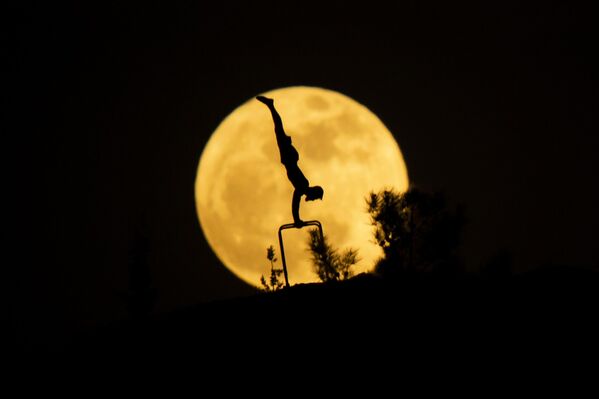 يظهر القمر مكتملا خلف صورة ظلية لرجل يمارس الجمباز في  العراق - سبوتنيك عربي