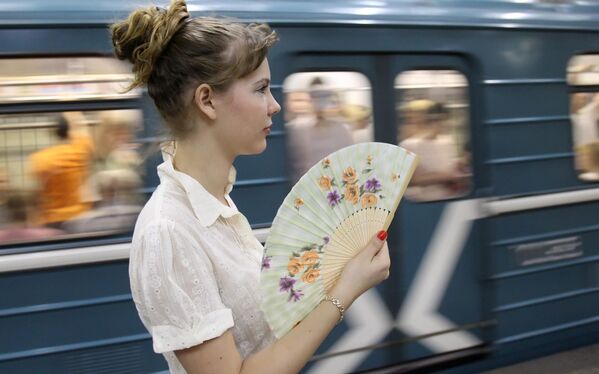 فتاة ترفرف بمروحة رفرفة قابلة للطي على رصيف محطة مترو في موسكو - سبوتنيك عربي