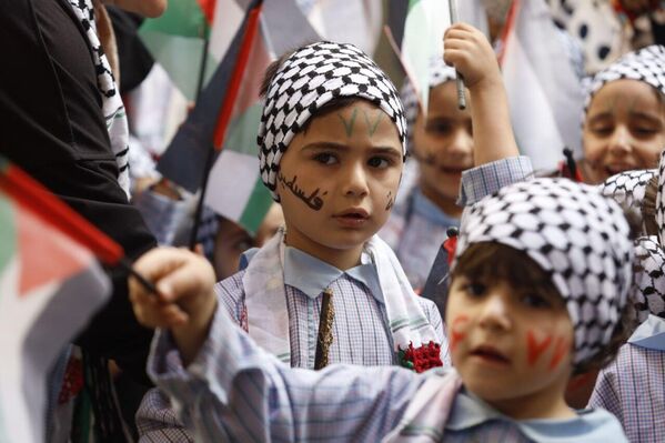 طفلان يكتبان على وجوهما اسم فلسطين ويرتديان الزي الفلسطيني التقليدي. - سبوتنيك عربي