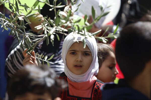 إحدى الأطفال المشاركات في المسيرة وهي تحمل غصن زيتون. - سبوتنيك عربي