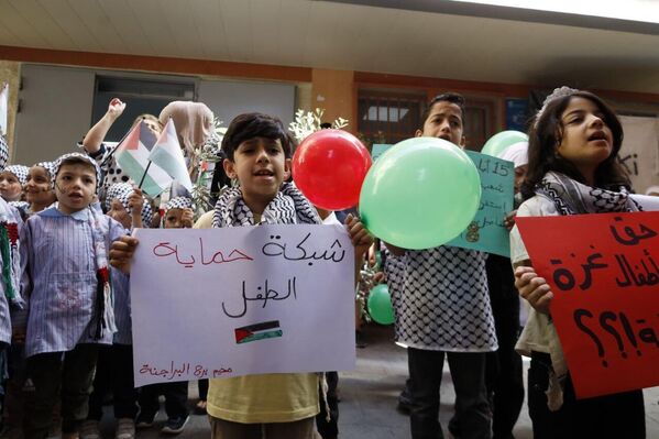 أطفال يحملون لافتات تدعو لحماية أطفال غزة. - سبوتنيك عربي