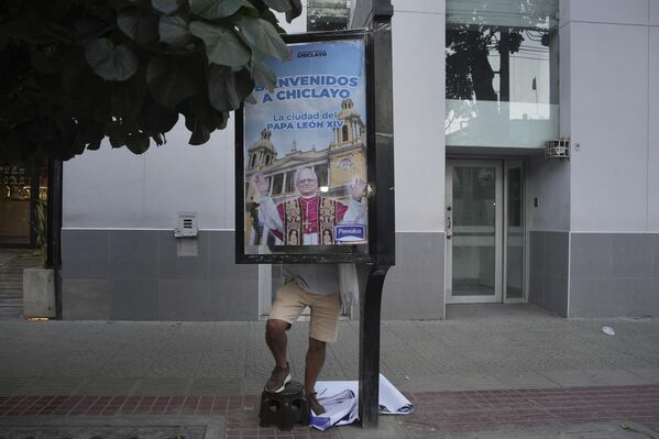 عامل يضع ملصقًا للبابا ليو الرابع عشر المنتخب حديثًا، على لوحة إعلانات في أحد شوارع بيرو - سبوتنيك عربي