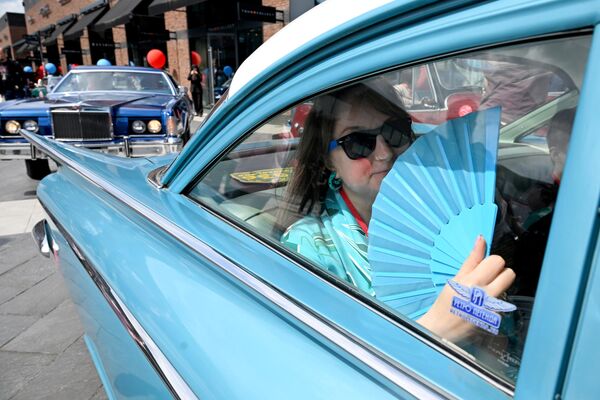 فتاه ترتدي زيل مشابها للون سيارتها في التجمع السنوي للسيارات الكلاسيكية على أراضي مجمع التسوق "أرخانغيلسكوي أوتليت" - سبوتنيك عربي