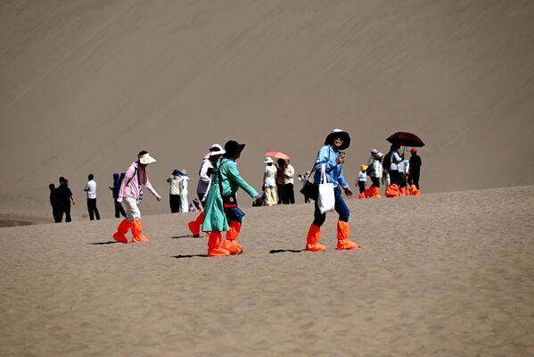 سياح يزورون جبل "مينغشا" وموقع "الهلال الربيعي" ذي الطبيعة الخلابة، دونهوانغ، مقاطعة غانسو، الصين - سبوتنيك عربي