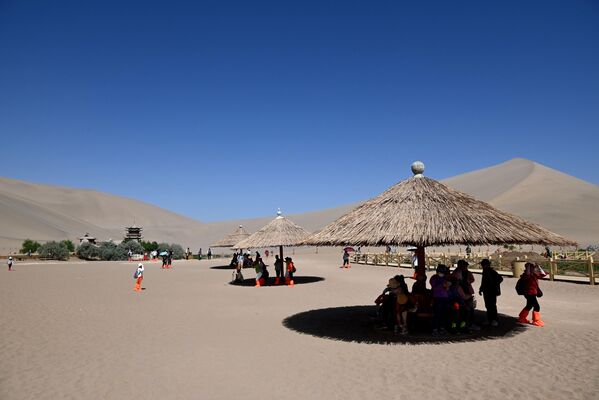 سياح يحتمون بالظل من شمس مدينة دونهوانغ القوية - سبوتنيك عربي