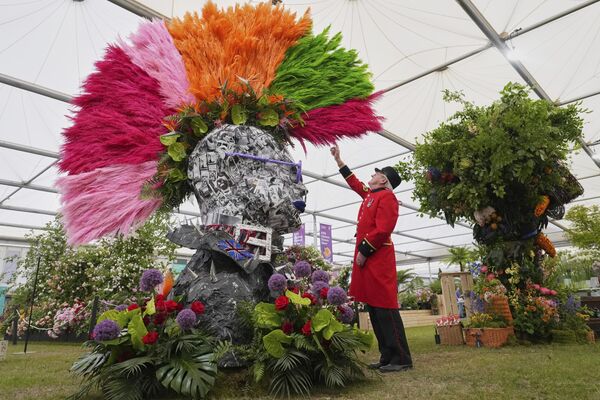 بيتر ويلسون، متقاعد من تشيلسي، يمد يده ليلمس رأس &quot;بانكس&quot; بتصفيفة &quot;موهوك&quot; مصنوعة من عشب البامباس والأزهار الاستوائية والأوراق، من تصميم ريكي بول فلاورز، في معرض تشيلسي للزهور التابع للجمعية الملكية البريطانية للبستنة في لندن، الاثنين 19 مايو 2025 - سبوتنيك عربي