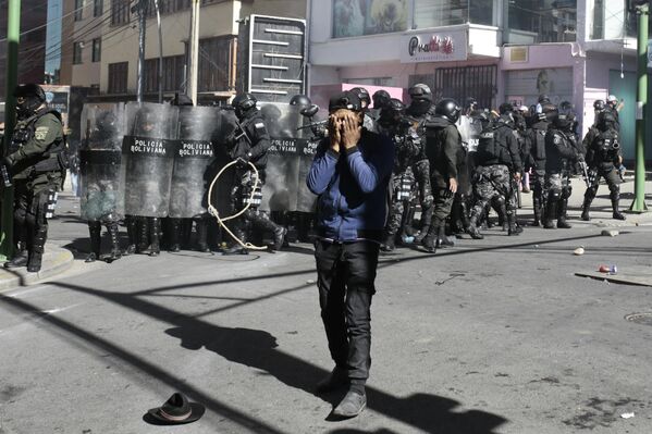 رجل مصاب بالغاز المسيل للدموع أمام رجال الشرطة خلال مظاهرة في لاباز، بوليفيا. - سبوتنيك عربي