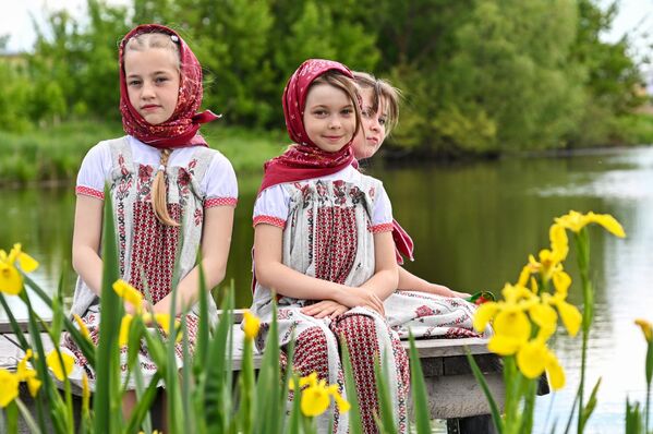 فتيات صغيرات مشاركات في المهرجان يجلسن وسط الزهور على ضفاف النهر. - سبوتنيك عربي