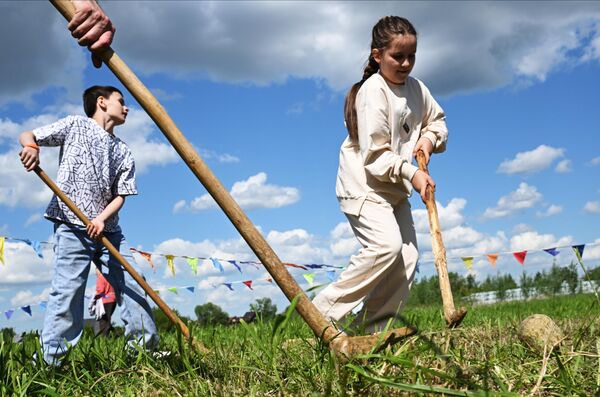 صورة أثناء لعب المشاركين في مهرجان &quot;كارافون&quot; لعبة الباندي وسط مروج خضراء. - سبوتنيك عربي